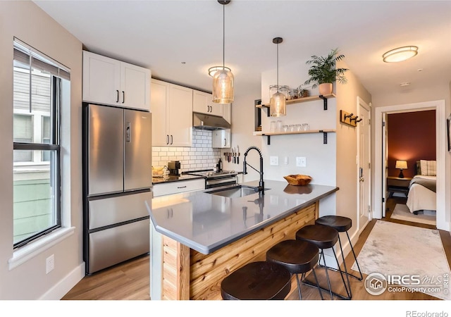 kitchen with sink, a breakfast bar area, white cabinets, hanging light fixtures, and stainless steel appliances