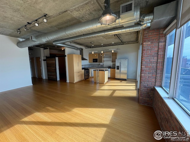 kitchen with a kitchen island, plenty of natural light, wall chimney exhaust hood, and appliances with stainless steel finishes