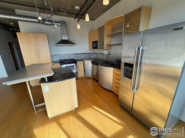 kitchen with a center island, light hardwood / wood-style flooring, appliances with stainless steel finishes, pendant lighting, and wall chimney range hood