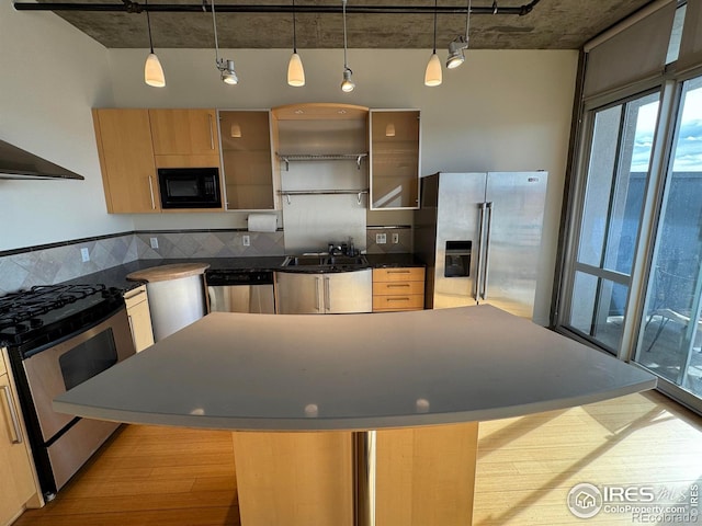 kitchen with pendant lighting, a center island, appliances with stainless steel finishes, and light brown cabinetry