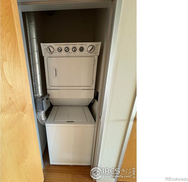 laundry room featuring stacked washer and clothes dryer and hardwood / wood-style floors