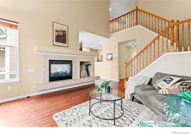 living room featuring hardwood / wood-style floors, a towering ceiling, and a tile fireplace