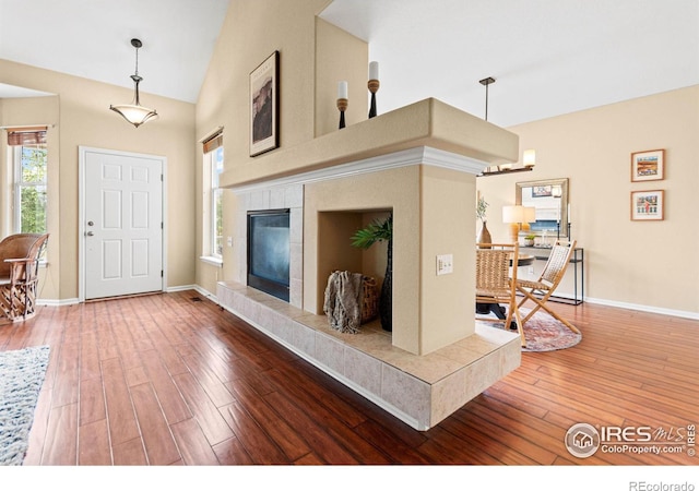 living room featuring high vaulted ceiling, hardwood / wood-style floors, and a fireplace