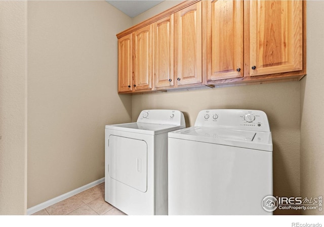 clothes washing area featuring cabinets, washer and clothes dryer, and light tile patterned floors