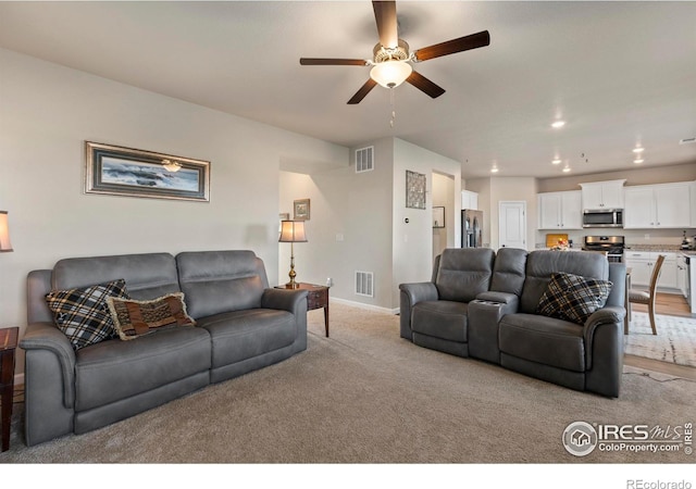 carpeted living room with ceiling fan