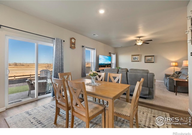 dining space with ceiling fan, a water view, and light wood-type flooring