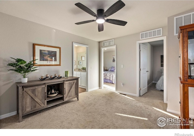 interior space with connected bathroom, light carpet, and ceiling fan