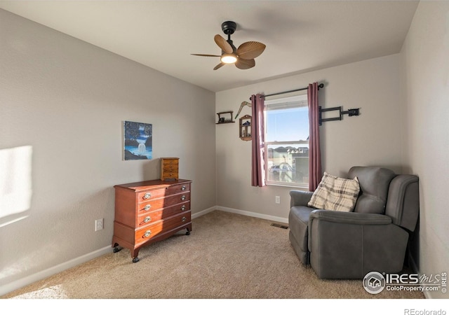 living area featuring light carpet and ceiling fan