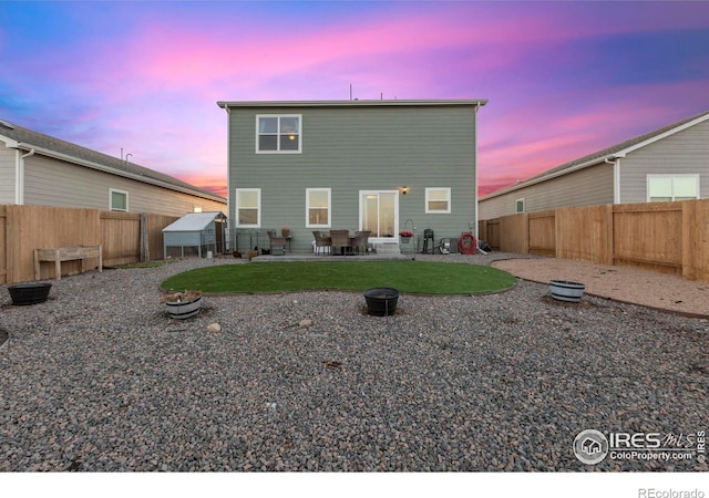 back house at dusk with a yard and a patio