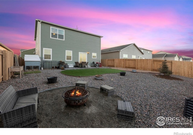 back house at dusk with a patio area and a fire pit