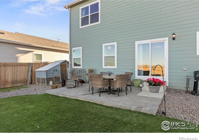 back of property featuring a yard, an outdoor structure, and a patio