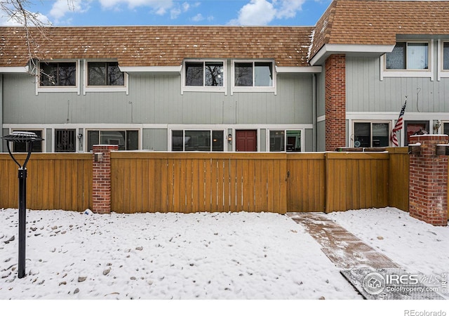 snow covered house with a fenced front yard