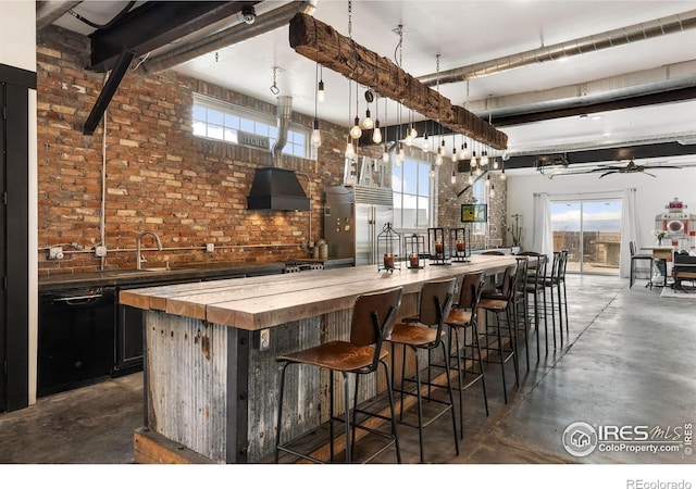 bar featuring custom exhaust hood, decorative light fixtures, dishwasher, stainless steel built in fridge, and brick wall