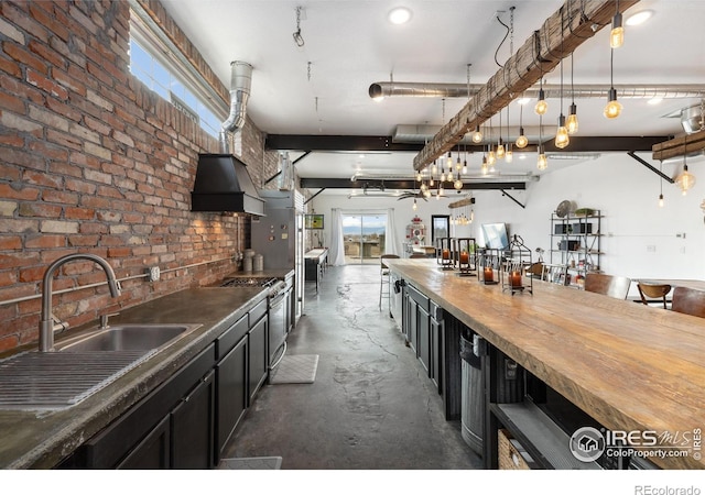 kitchen with sink, butcher block counters, stainless steel range with gas stovetop, brick wall, and decorative light fixtures