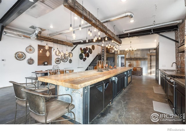 kitchen featuring a breakfast bar, sink, gas range, hanging light fixtures, and a kitchen island