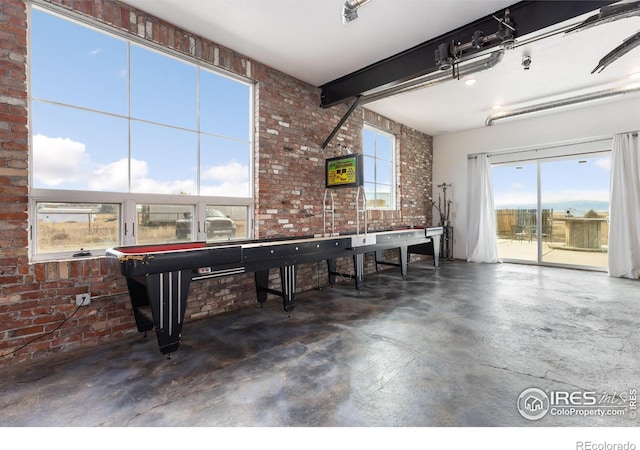 rec room with brick wall and beam ceiling