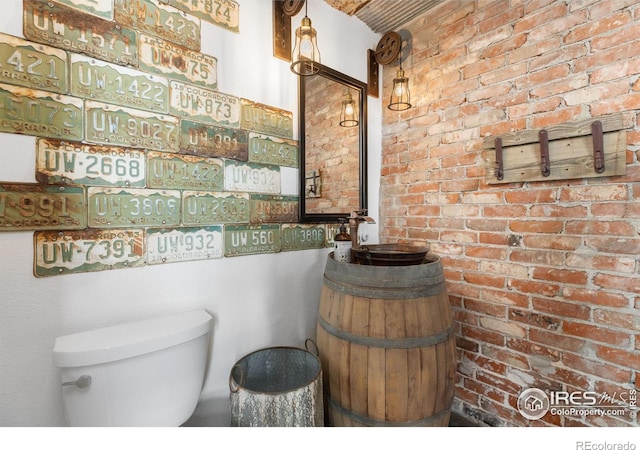 bathroom with brick wall and toilet