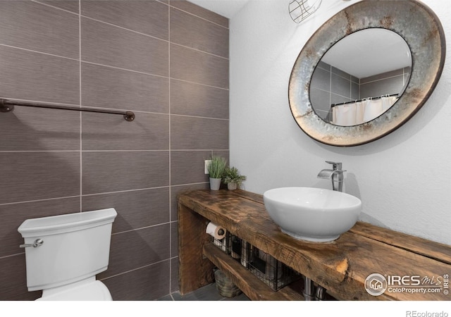 bathroom with tile walls, sink, and toilet