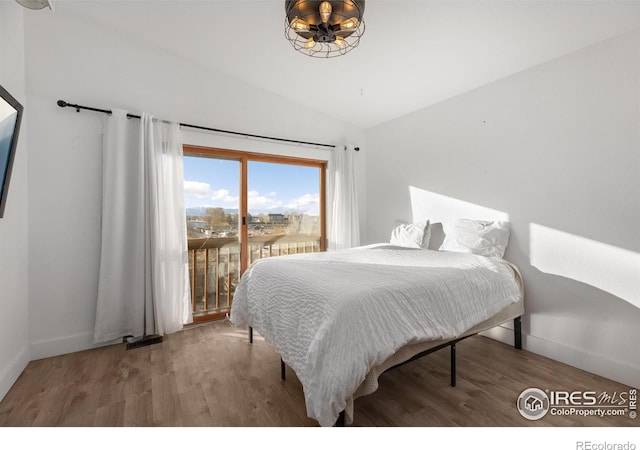 bedroom with access to exterior, vaulted ceiling, and hardwood / wood-style floors