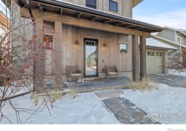 snow covered property entrance with a garage