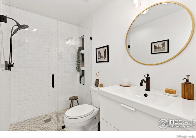 bathroom featuring vanity, a shower with shower door, and toilet