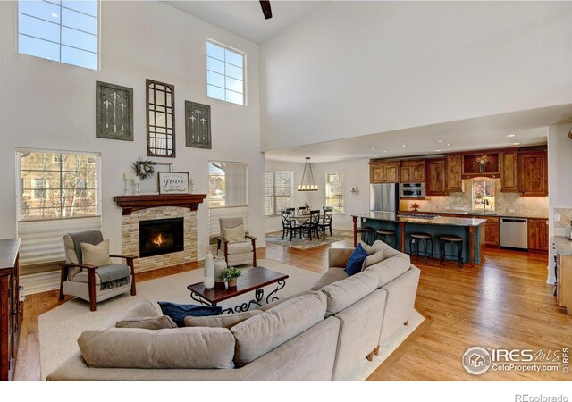 living room featuring a stone fireplace, sink, and light hardwood / wood-style flooring