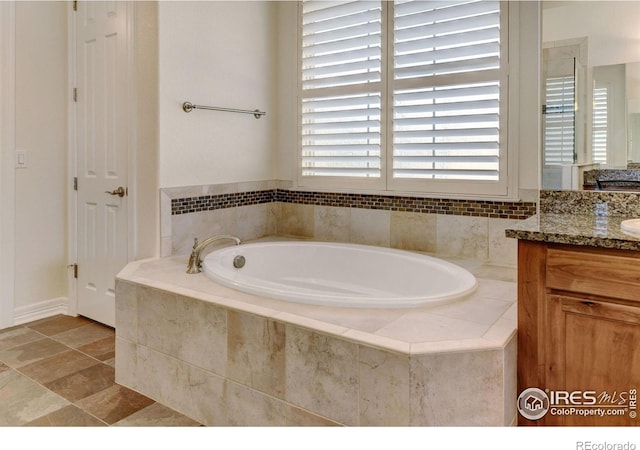 bathroom featuring a relaxing tiled tub and vanity