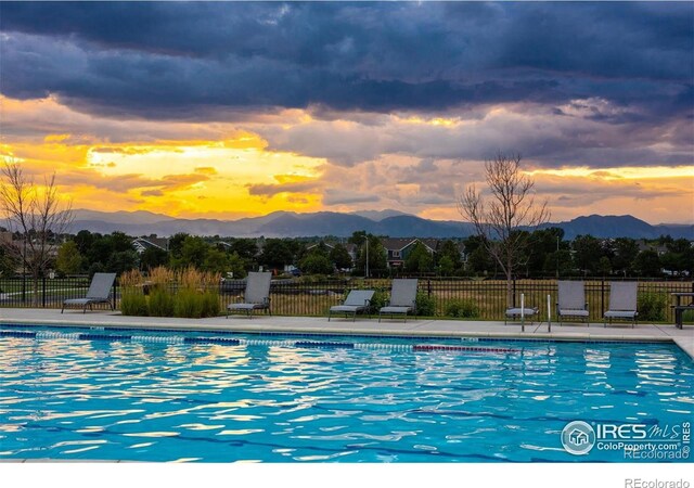 pool at dusk featuring a mountain view