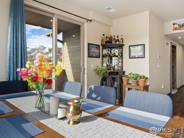 dining room featuring wood-type flooring, a mountain view, and bar