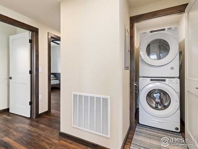 washroom featuring dark wood-type flooring and stacked washing maching and dryer