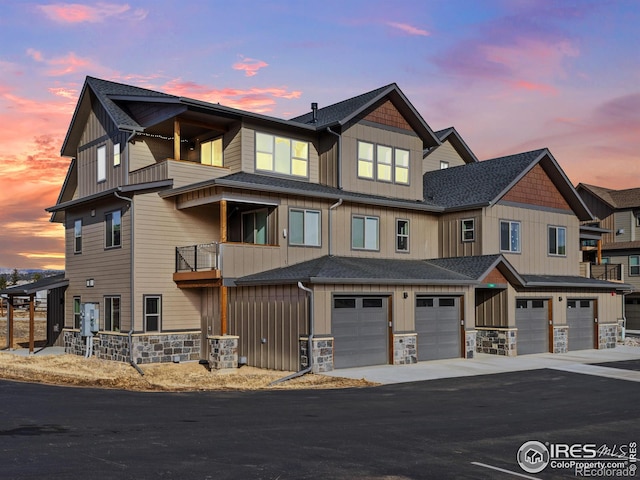 townhome / multi-family property featuring board and batten siding, a garage, stone siding, and roof with shingles