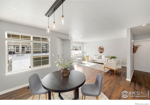dining room featuring a textured ceiling, wood finished floors, and baseboards