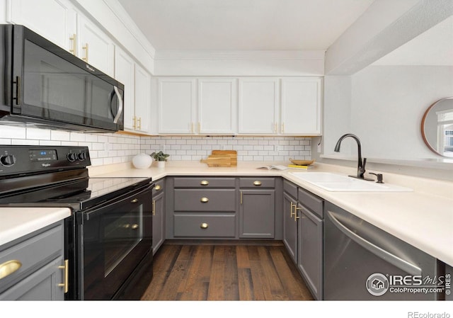kitchen featuring dark wood-style floors, a sink, gray cabinetry, black appliances, and backsplash