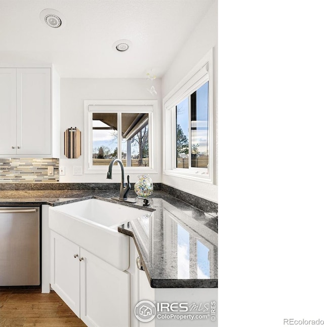 kitchen featuring tasteful backsplash, white cabinetry, sink, dark stone countertops, and stainless steel dishwasher