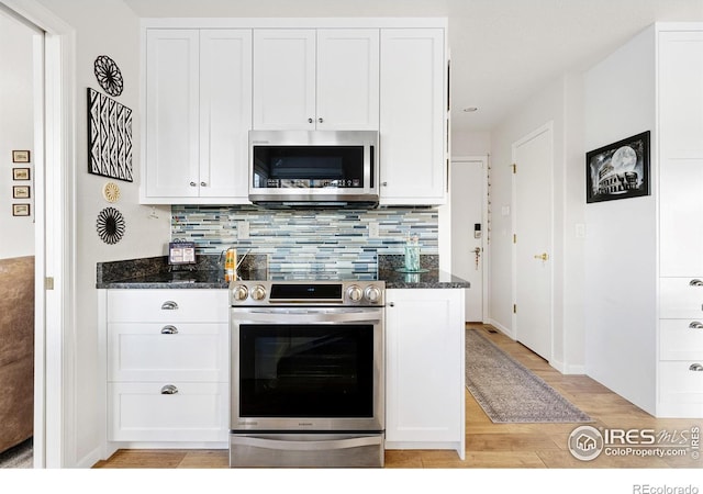 kitchen with white cabinetry, stainless steel appliances, and dark stone counters