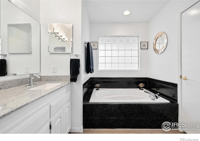 bathroom featuring vanity and tiled bath