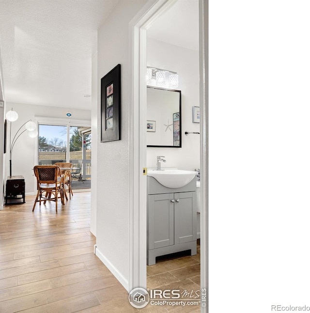 hallway featuring sink, a textured ceiling, and light wood-type flooring