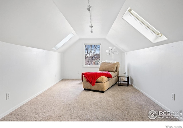 carpeted bedroom featuring lofted ceiling with skylight and rail lighting