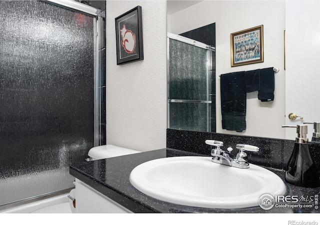 bathroom with vanity, toilet, and a shower with shower door