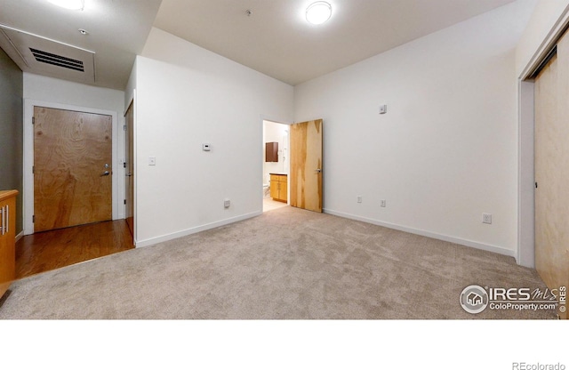 unfurnished bedroom with connected bathroom and light colored carpet