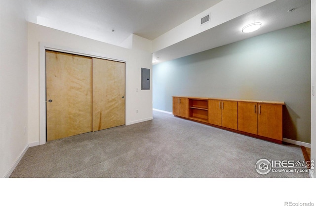 unfurnished bedroom featuring light colored carpet, electric panel, and a closet