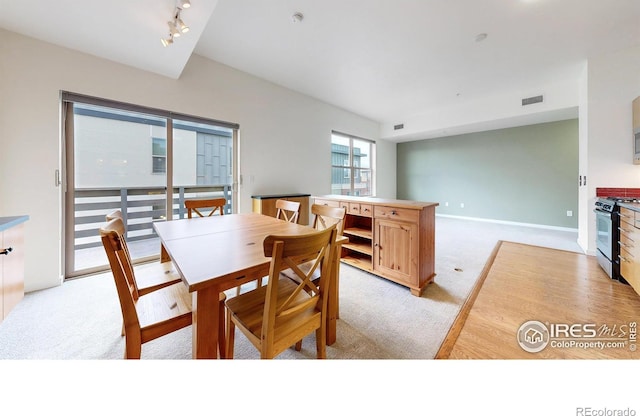 dining room with light colored carpet and rail lighting