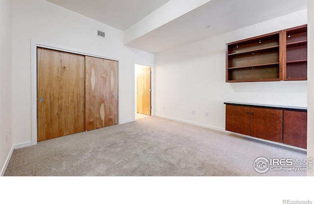 unfurnished bedroom featuring light colored carpet and a closet