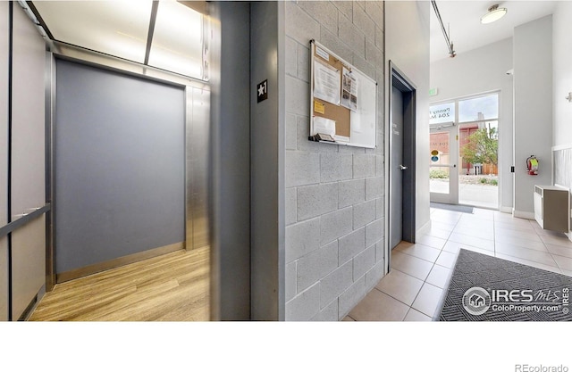 hall featuring light tile patterned floors and elevator