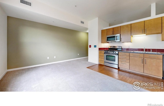 204 Maple St Unit 403, Fort Collins, CO 80521 - kitchen featuring appliances with stainless steel finishes, carpet flooring, dark countertops, a sink, and baseboards