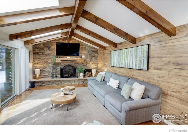 living area with wood walls, a fireplace, and vaulted ceiling with beams