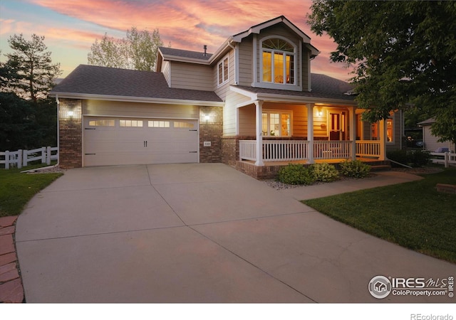 view of front of home featuring a garage, covered porch, and a lawn