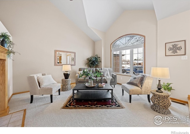 carpeted living room with high vaulted ceiling