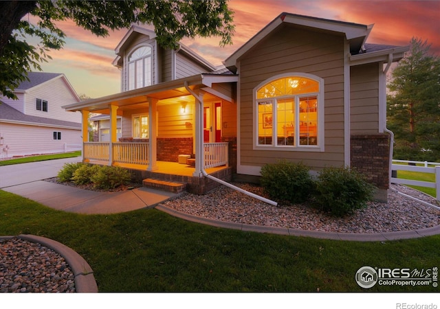 view of front of house with covered porch and a lawn