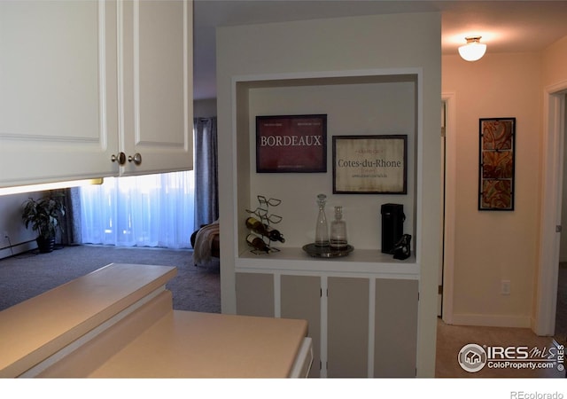 kitchen featuring carpet floors and white cabinets